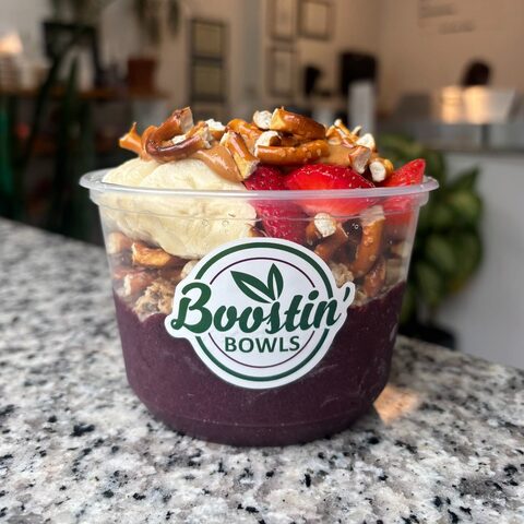 Purple bowl with granola, banana, and pretzel pieces