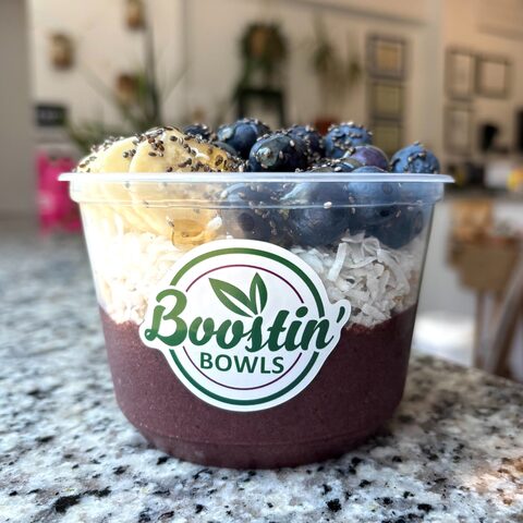 Purple bowl with granola, banana, blueberries, chia seeds, and honey