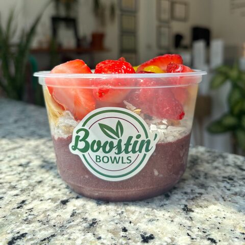 Purple bowl with granola, banana, mango, and coconut shavings